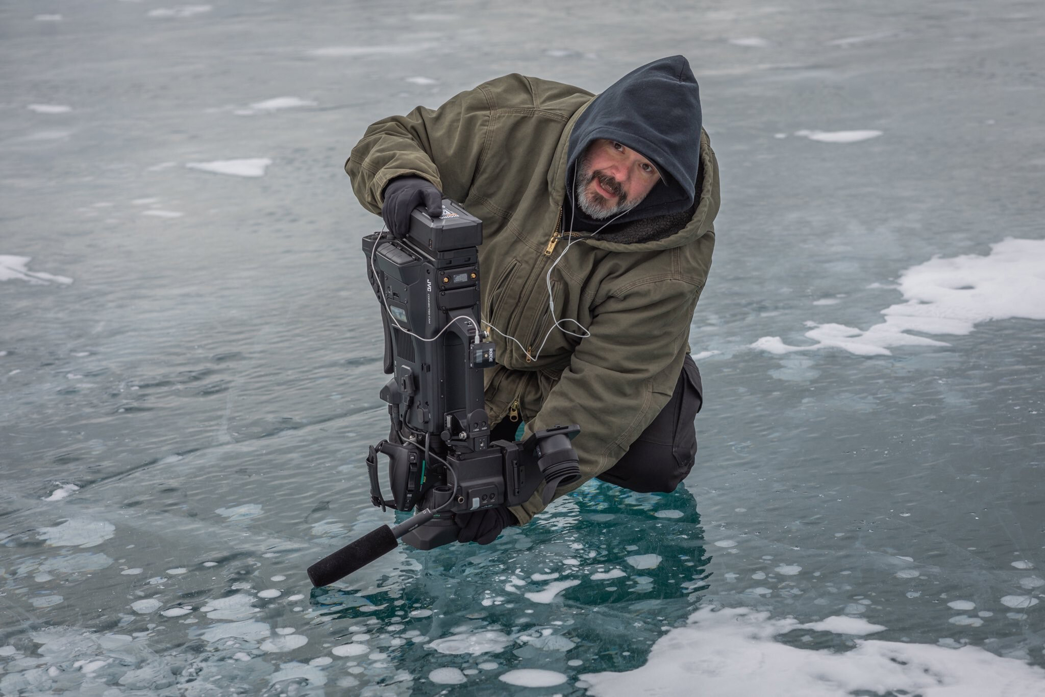 Chris Koehn capturing macro footage of methane bubbles trapped in the ice at Abraham Lake in Alberta, Canada. Credit: Keith Moore Photography.